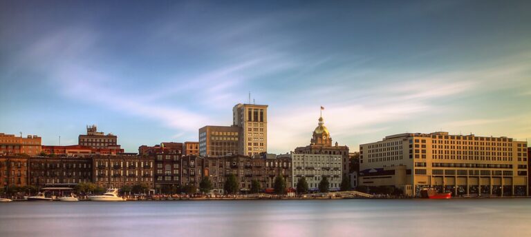 A city skyline with buildings and water in the foreground.